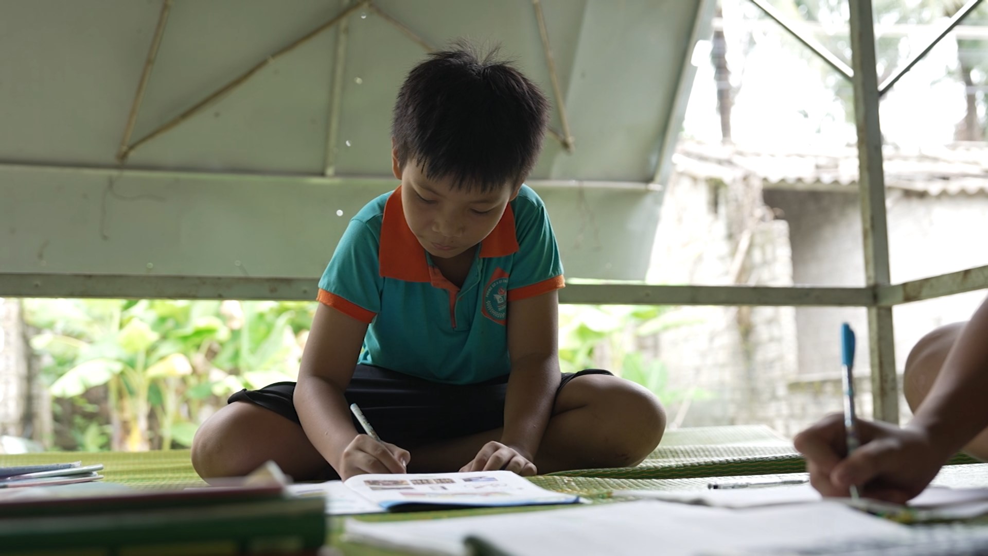 Trong căn nhà cũ, em Huy Nam vẫn miệt mài viết từng trang vở, nuôi dưỡng ước mơ cho tương lai  dù thiếu vắng vòng tay cha mẹ.