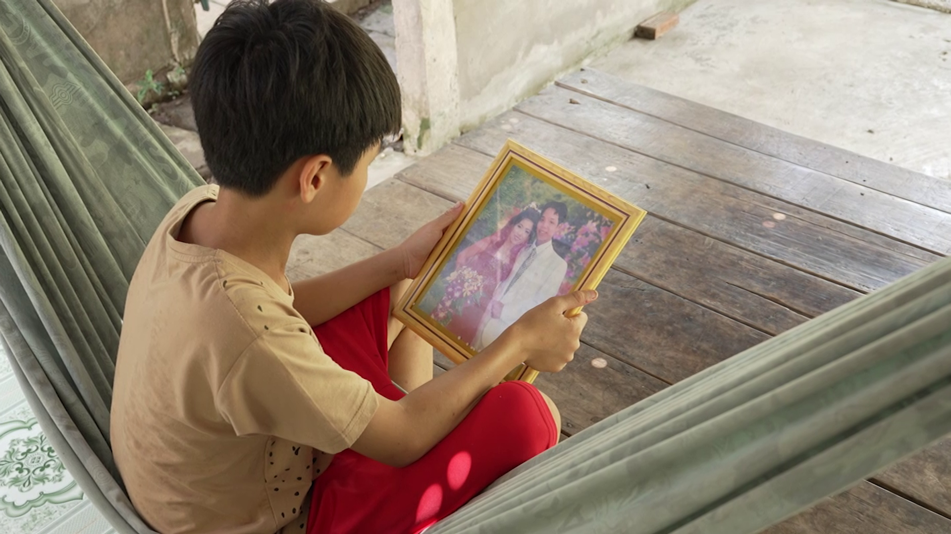Phước Ngoan lặng lẽ ngắm nhìn bức ảnh của cha mẹ